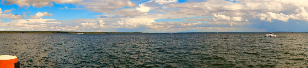 Fototapeta premium Stormy sky over a lake. Dark clouds with rays of sunshine that make the water sparkle