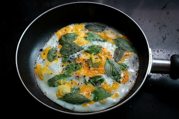 fried egg with sweet basil and holy basil in the pan