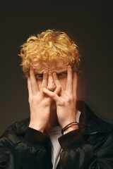 A young man showcases his unique holiday fashion with a playful pose, playfully obscuring his face while evoking a festive spirit.