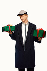 This fashionable man showcases contemporary holiday attire while joyfully holding two beautifully wrapped Christmas presents.
