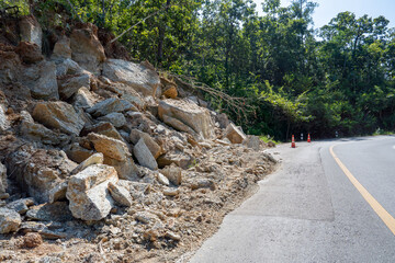 Landslide debris on winding road surrounded by trees and vegetation © somchairakin