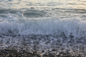 Storm near the coastline. Splashes of a wave on the beach. Wave near the shore. Water in motion.