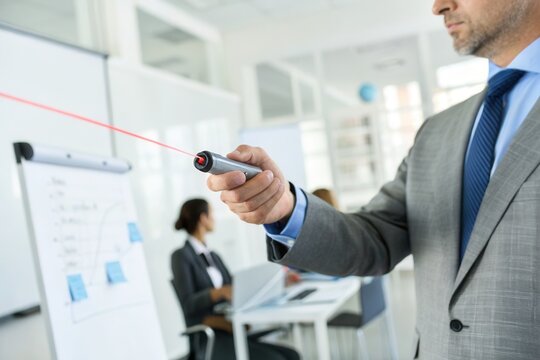 A business professional uses a laser pointer to highlight details in a presentation to colleagues.