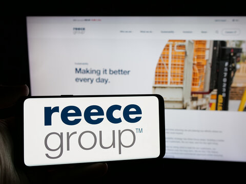 Stuttgart, Germany - 10-30-2024: Person holding smartphone with logo of plumbing and bathroom company Reece Limited on screen in front of website. Focus on phone display.