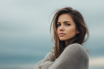 Fototapeta premium Young woman with long hair poses against a moody sky at an outdoor location