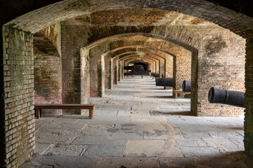 Historical brick fort with arched corridors, antique cannons, and weathered structures, showcasing intricate masonry and military architecture under natural light.