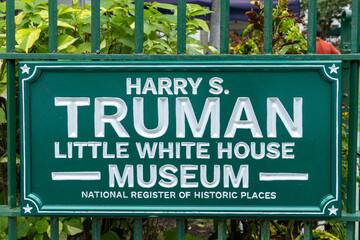 Sign for the Harry S. Truman Little White House Museum, part of the National Register of Historic Places, surrounded by greenery.