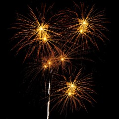 A dazzling display of golden fireworks bursting in the night sky, creating a mesmerizing and...
