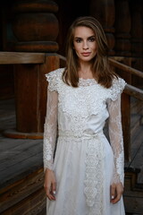 A young girl poses in a boho wedding dress, cowboy boots, a cowboy hat, and a denim jacket.