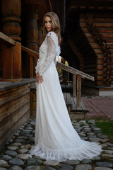 A young girl poses in a boho wedding dress, cowboy boots, a cowboy hat, and a denim jacket.