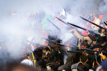 Smoking guns and muskets with a lot of black powder smoke, fired by a historic detachment of musketeers in historical clothing from the Dutch Revolution period during the golden age of the Netherlands