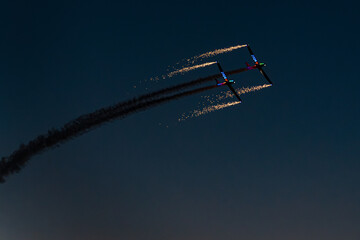 Ayr Show, Ayr, Scotland, 06 09 2024. Two planes fly side by side in the night sky, with sparkling fireworks streaking from their wings.