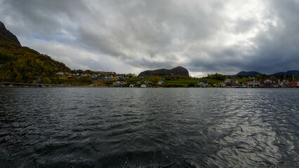 Coastal Village with Mountains and Cloudy Sky