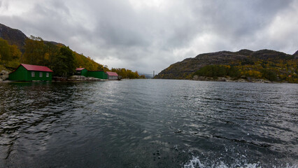 Scenic Fjord with Green Cabins and Autumn Colors
