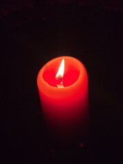 A red candle shining alone in the dark