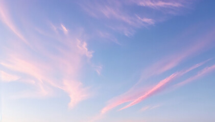 Obraz premium Pastel pink clouds drift across a serene blue sky at dawn or dusk, creating a breathtaking and dreamy spectacle.
