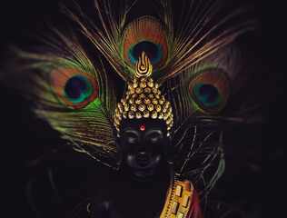 laughing buddha idol with peacock feather in the background.