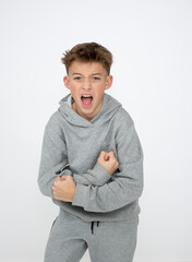 cool young 12 year old boy with grey hoody sweater posing in front of white background, having fun