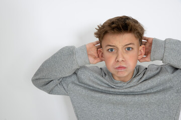 cool young 12 year old boy with grey hoody sweater posing in front of white background, having fun