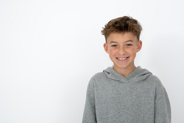 cool young 12 year old boy with grey hoody sweater posing in front of white background, having fun