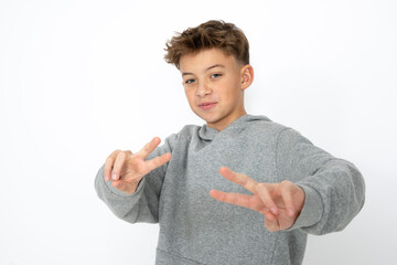 cool young 12 year old boy with grey hoody sweater posing in front of white background, having fun