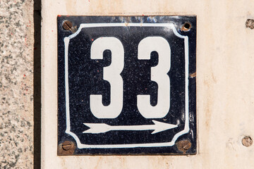 Weathered enameled plate of street address with number 33