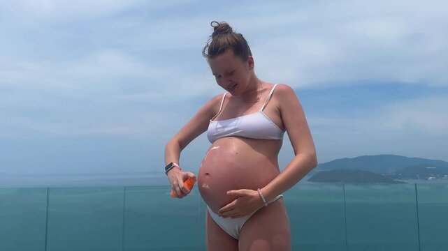beautiful pregnant young girl with big belly uses cga cream in summer before tanning