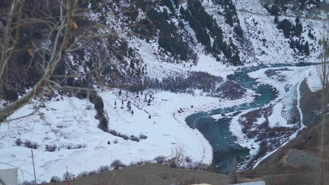 Closeup shot of river Chandra flowing in the snow covered Himalayan mountain range during the winter season as seen from Gondhla village in Lahaul and Spiti district, Himachal Pradesh, India.