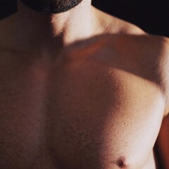 Fototapeta premium A close-up of a man's chest showing bio-luminescent circuitry intertwined with organic muscle fibers, softly pulsating with light. 