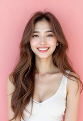 Fototapeta premium A young Asian woman with warm smile wearing a white sleeveless top against a pink background