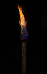 Ancient burning wooden torch on black background.