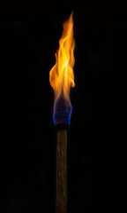 Ancient burning wooden torch on black background.