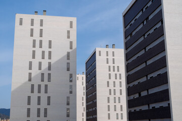 Tall residential apartment buildings with white facades and modern design under a clear blue sky