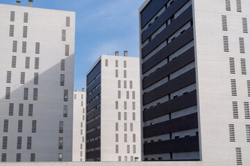 Bright white residential towers with black facade sections and geometric patterns under a sunny sky