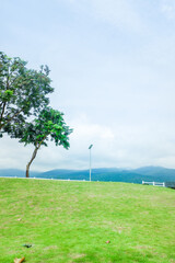 White fence with green grass hill and mountain,blue sky,Lush green golf Course,rest and relax in park near city,big tree in garden,Green grass field,Nature landscape,space for text.