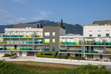 White and grey apartment complex with colorful balconies and a scenic mountain backdrop