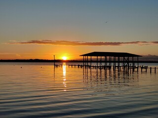 Obraz premium Sunset over tranquil lake and dock.