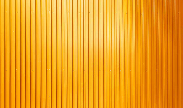real chrome yellow corrugated metal sheet wall showing vertical pattern, bolts, screw. modern industrial gold metal sheet wall facade. wide surface of yellow aluminum wall texture use for design.