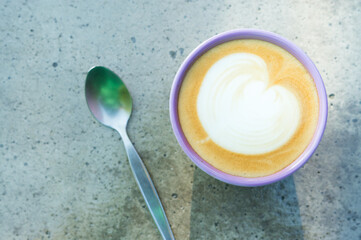 Hot latte coffee with spoon on gray table.