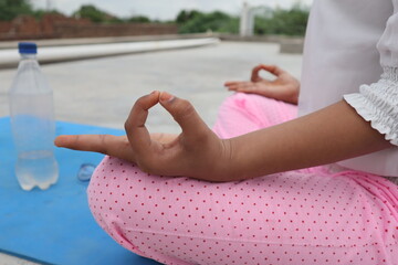 Close-up of hands in a meditation pose, resting on knees with fingers forming a mudra, symbolizing...