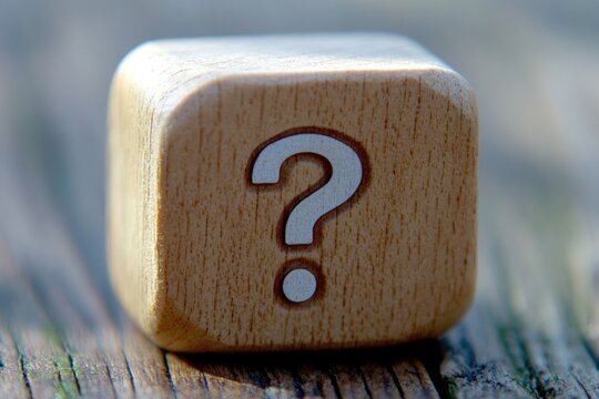 A wooden game dice with a question mark symbol on one side, suitable for use in games, puzzles and problem-solving activities - Powered by Adobe