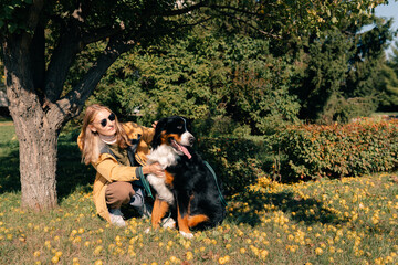 Fototapeta premium Female Walks a Bernese Mountain Dog Near the Local Lake in the Park. People and Dogs