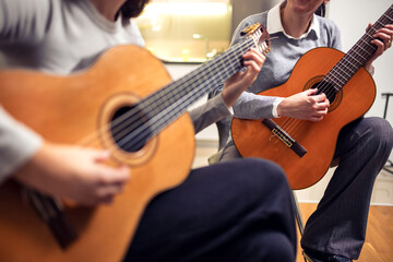 Obraz premium Mother and daughter playing guitar at home. A mother teaches her daughter to play the guitar.