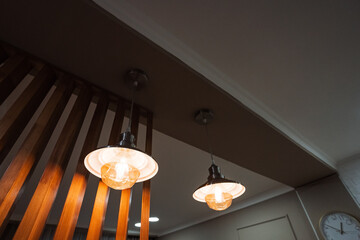 In a room adorned with wooden accents and features, two decorative lights elegantly hang from the...