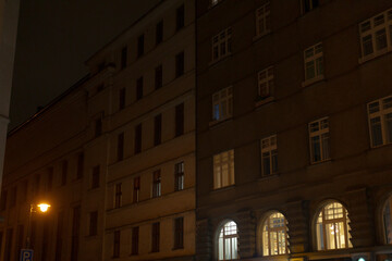 Nighttime urban landscape featuring residential buildings illuminated by street light, showcasing architecture and city life