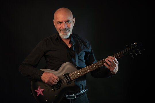Senior 65 years old man playing electric guitar