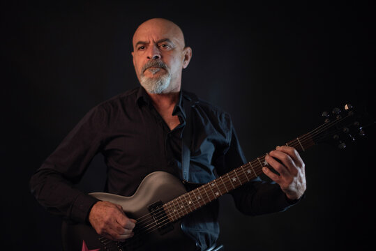 Senior 65 years old man playing electric guitar