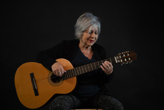 Senior 65 years old woman playing spanish guitar