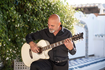 Senior man playing spanish guitar in his spanish patio