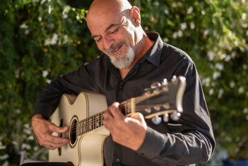 Man and woman, 65 years old, playing guitar in the Andalusian courtyard of their home
